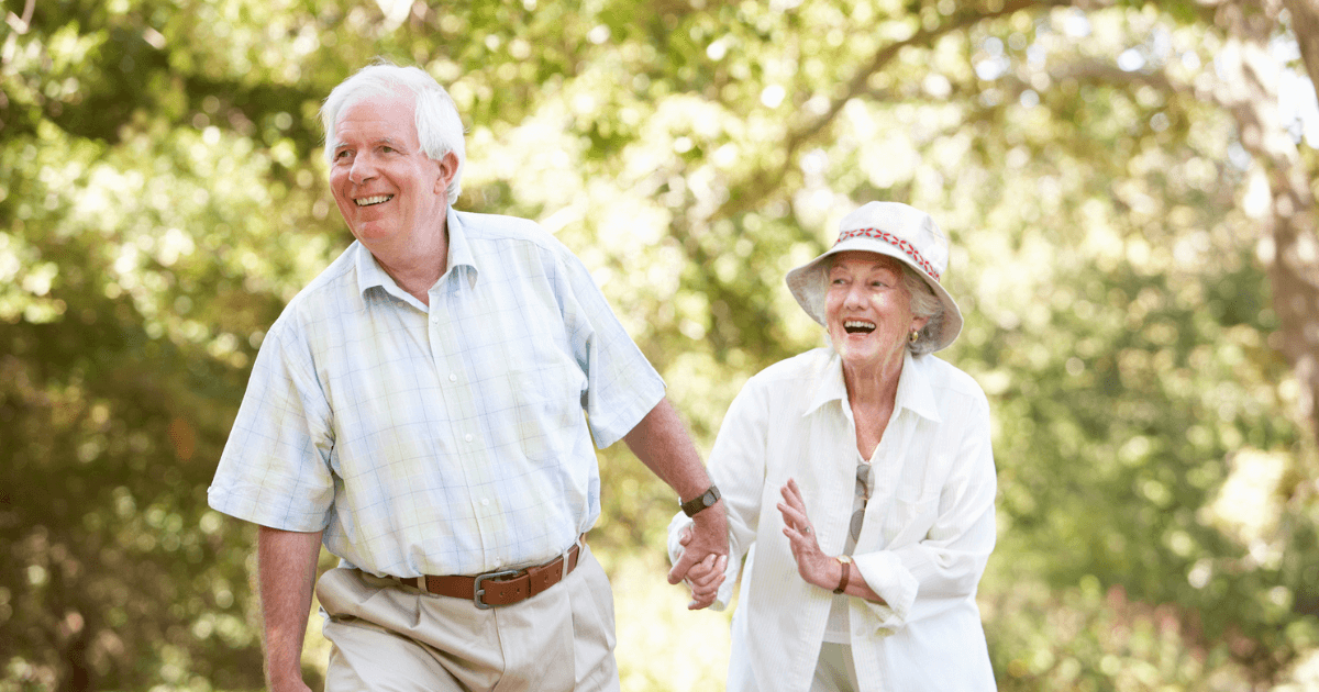 Elder man pulling senior woman laughing outdoors in Hillsborough Township parks