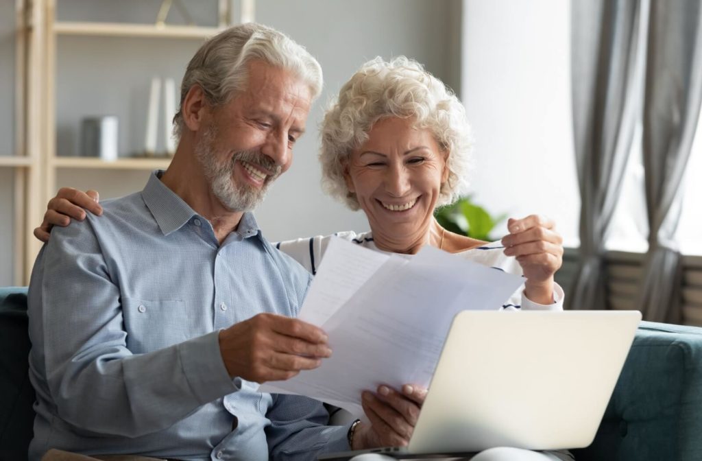 An older couple smiling while looking over paperwork that assesses their ability to perform activities of daily living.