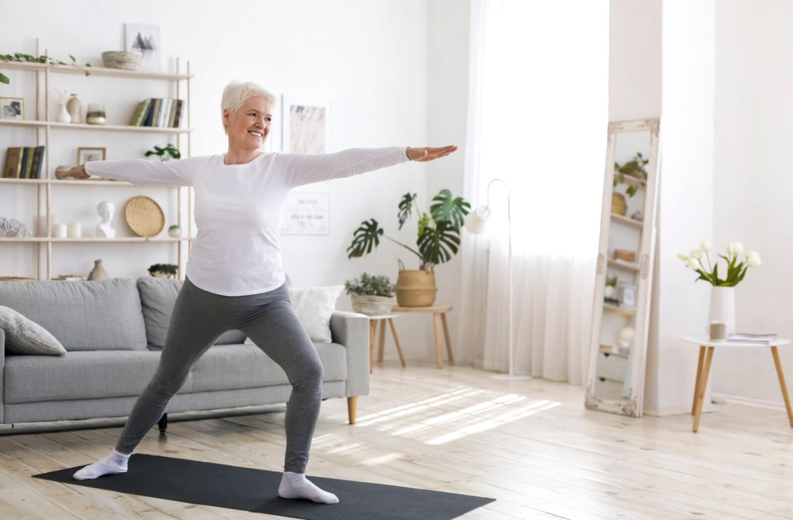 A senior living in assisted living enjoys some free time doing yoga in their private accommodations