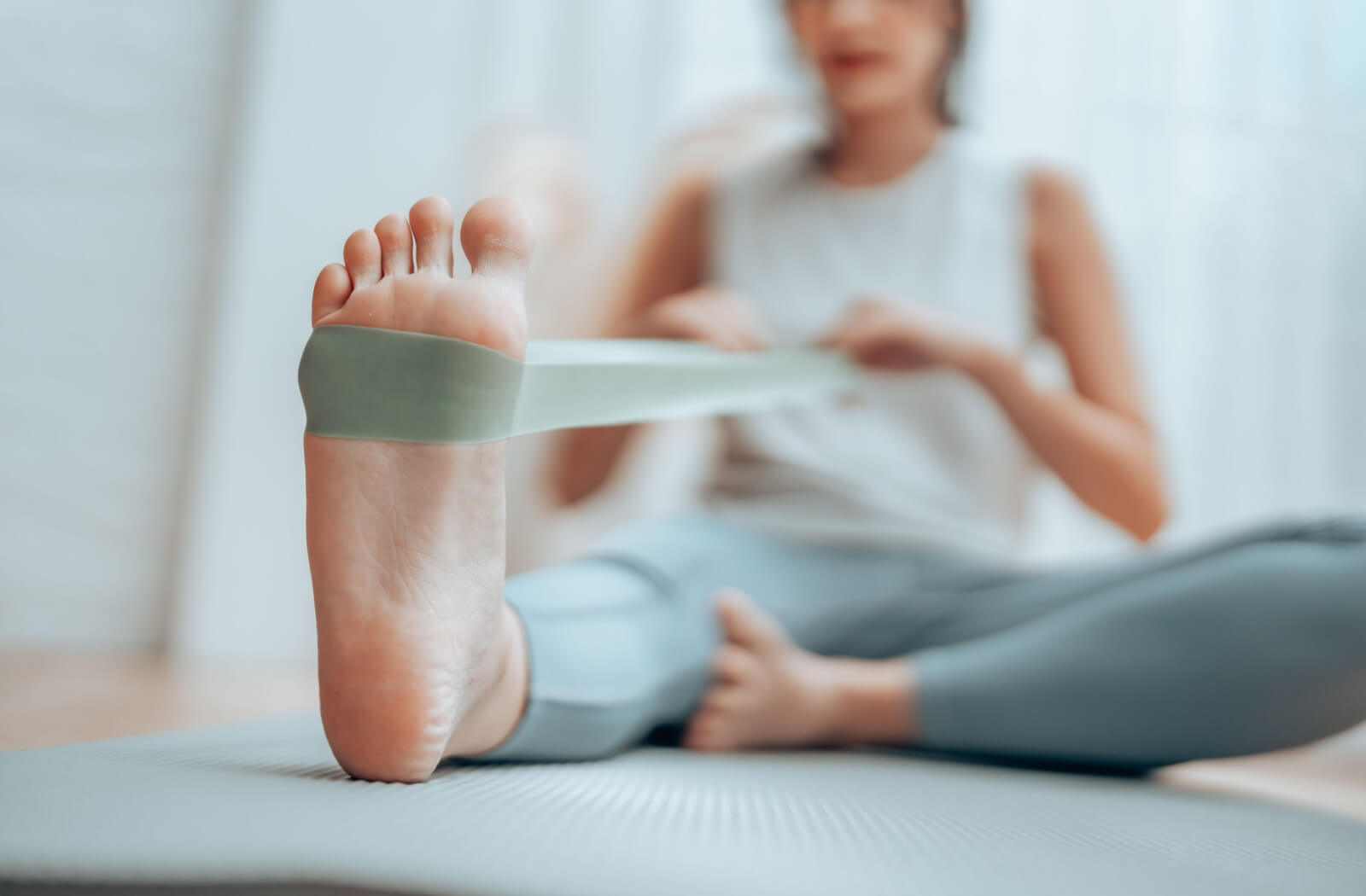 A senior pulls on an exercise band wrapped around their foot as a stretch to help reduce swelling around their ankles